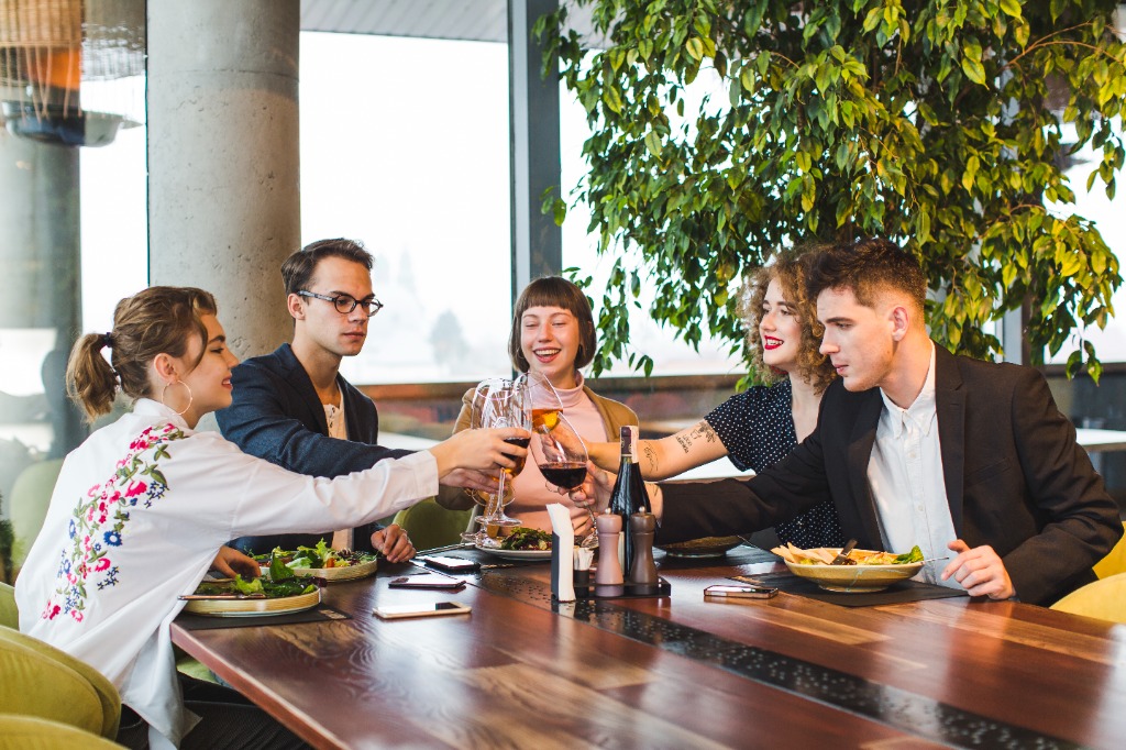 Young professionals raising glasses together in celebration over restaurant feast