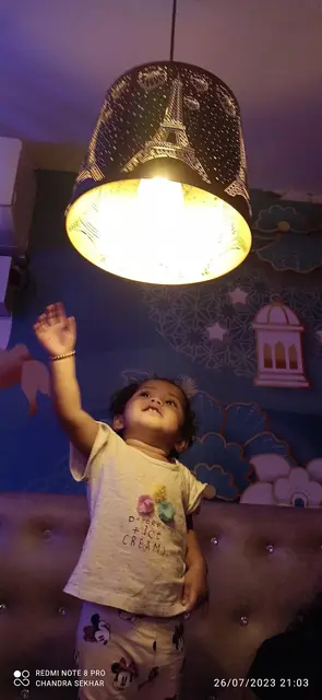 Little child reaching for the illuminated chandelier lamp inside restaurant booth